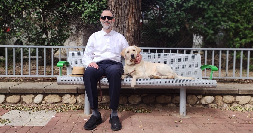 Erez is pictured seated with his guide dog.